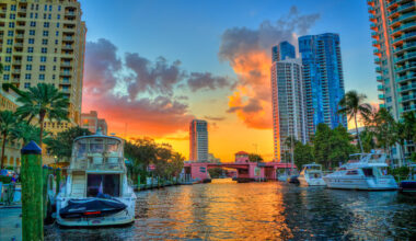 an orange sunset behind skyscrapers and a riverwalk