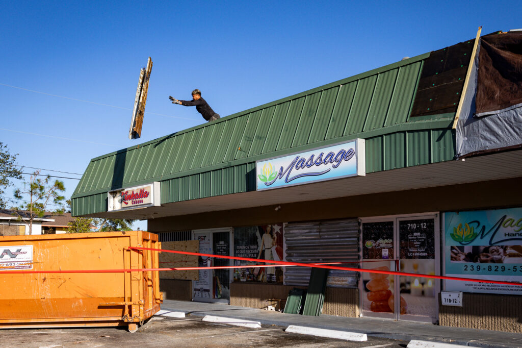 A construction worker discards debris from the roof of a restaurant damaged during a storm ahead of Hurricane Milton’s landfall on Oct. 14, 2024, in Fort Myers, Fla. Credit: Eva Marie Uzcategui/The Washington Post via Getty Images