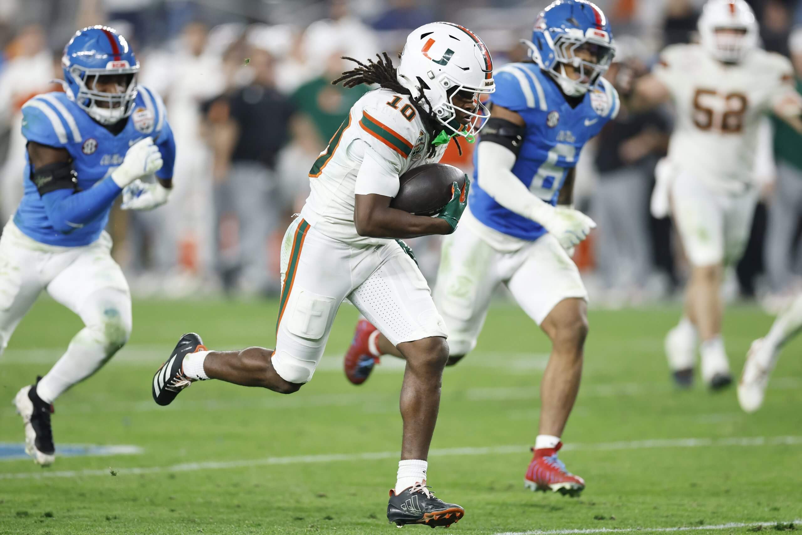 Miami receiver Malachi Toney runs with the ball with two Ole Miss defenders trailing him