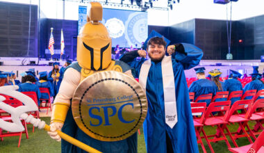 Titus the TItan Mascot and a graduate in blue cap and gown