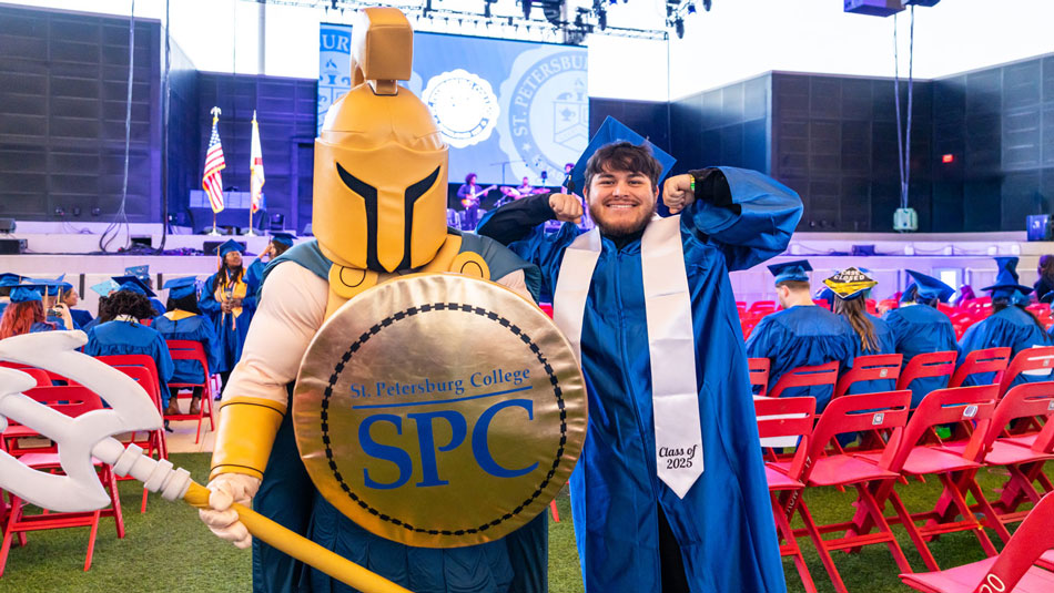 Titus the TItan Mascot and a graduate in blue cap and gown