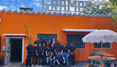 A group of people outside a place with orange walls that reads Gramps .