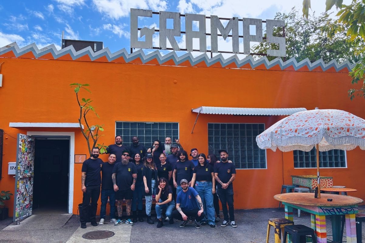 A group of people outside a place with orange walls that reads Gramps .