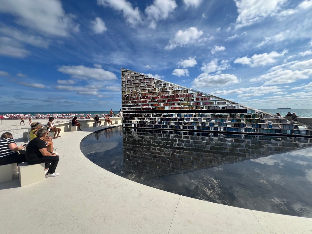 Es Devlin's Library of Us on the beach in Miami, featuring a moving installation of books arranged by color.