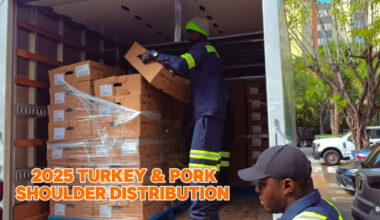 Two men emptying a U-Haul filled with boxes of pork shoulder