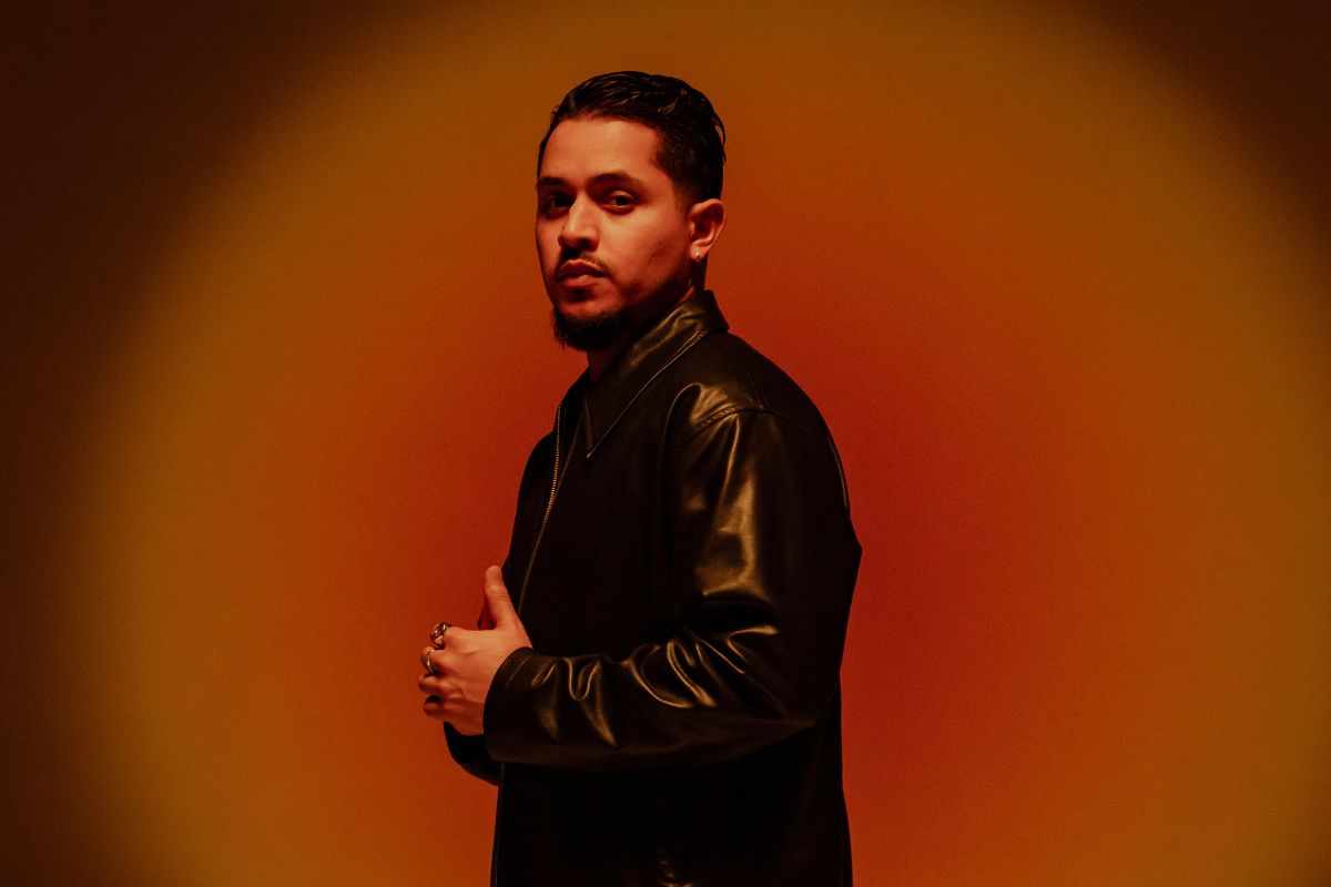 Portrait of a man wearing black against a red background.