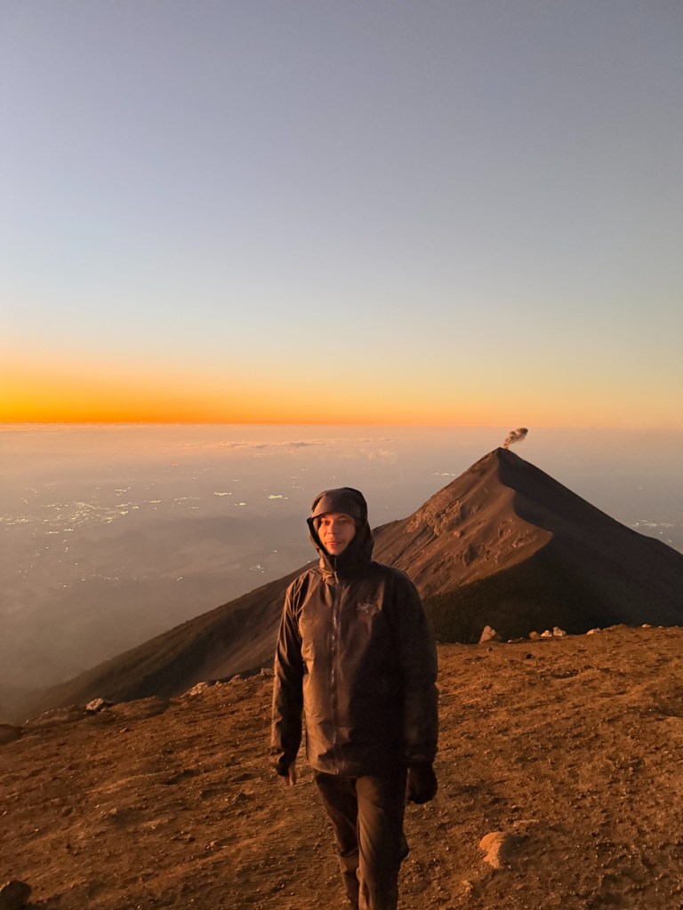 A man standing near the peak of a volcano.