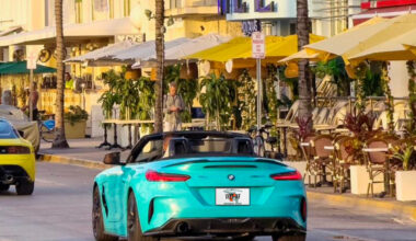 Teal BMW convertible on Ocean Drive with a Florida license plate that says "Wet AF."
