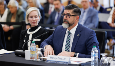 Manny Diaz Jr. and Rebecca Matthews sit at a table at the Board of Governors meeting.