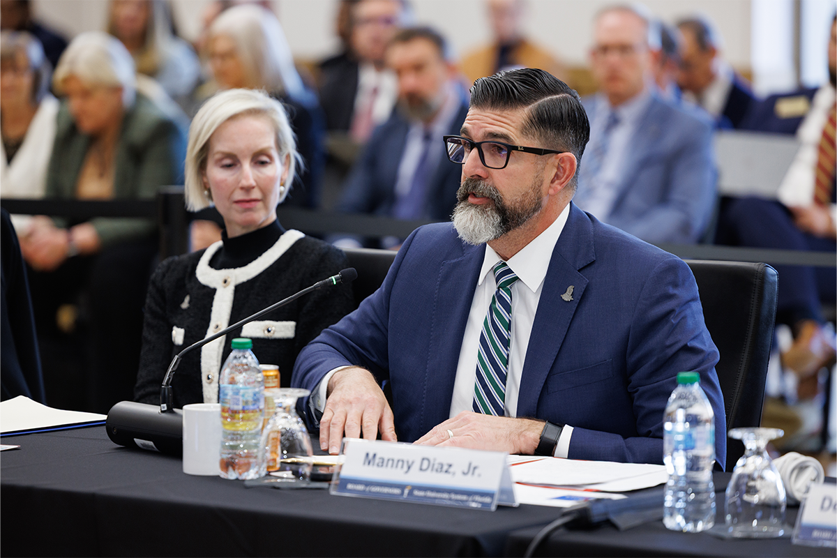 Manny Diaz Jr. and Rebecca Matthews sit at a table at the Board of Governors meeting.