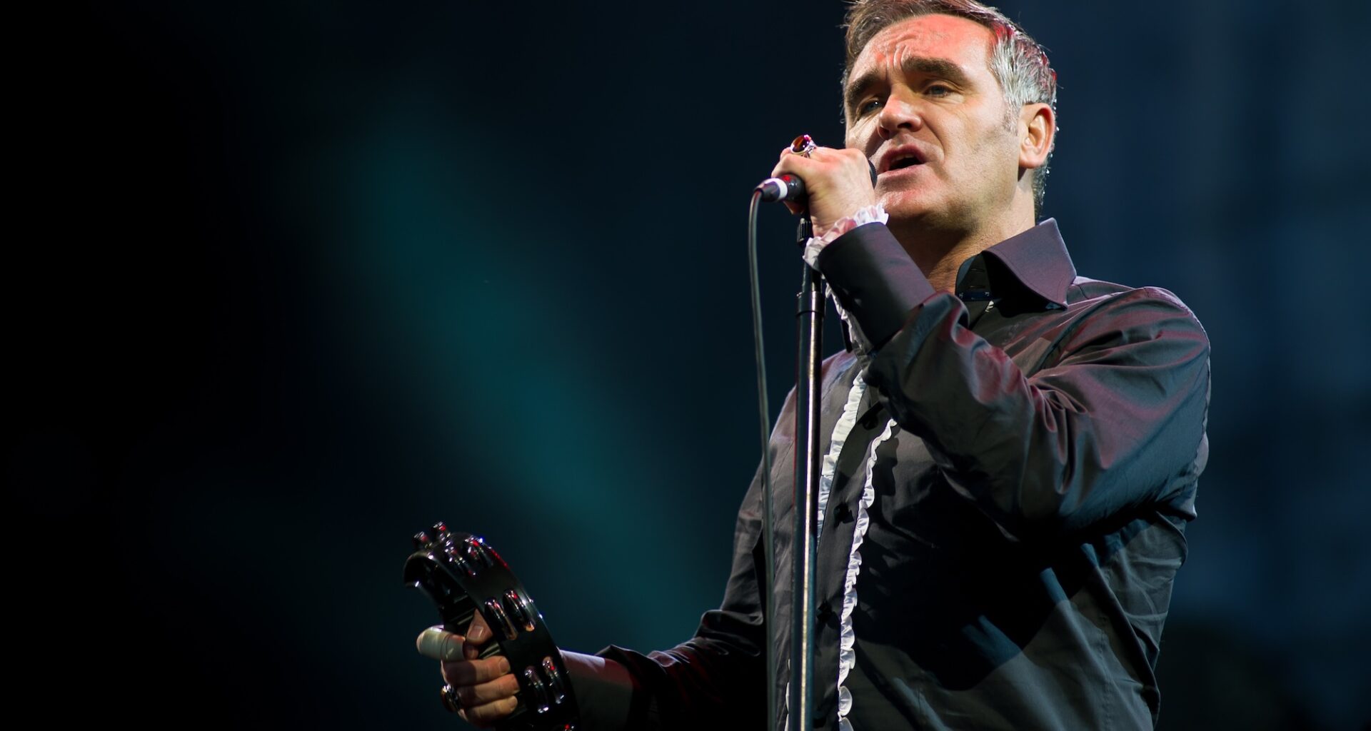 Photo of Morrissey performing on stage wearing a black shirt.