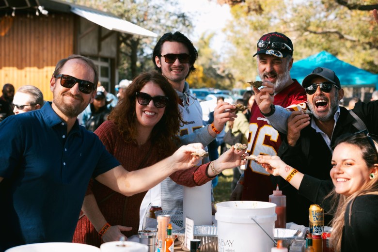 A group of people at an outdoor festival posing with oysters on the half shell