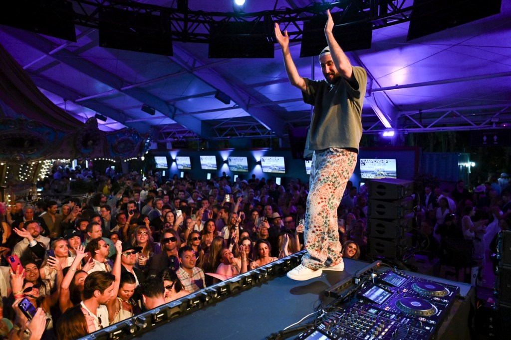 A man on a stage clapping his hands in front of a crowd. 
