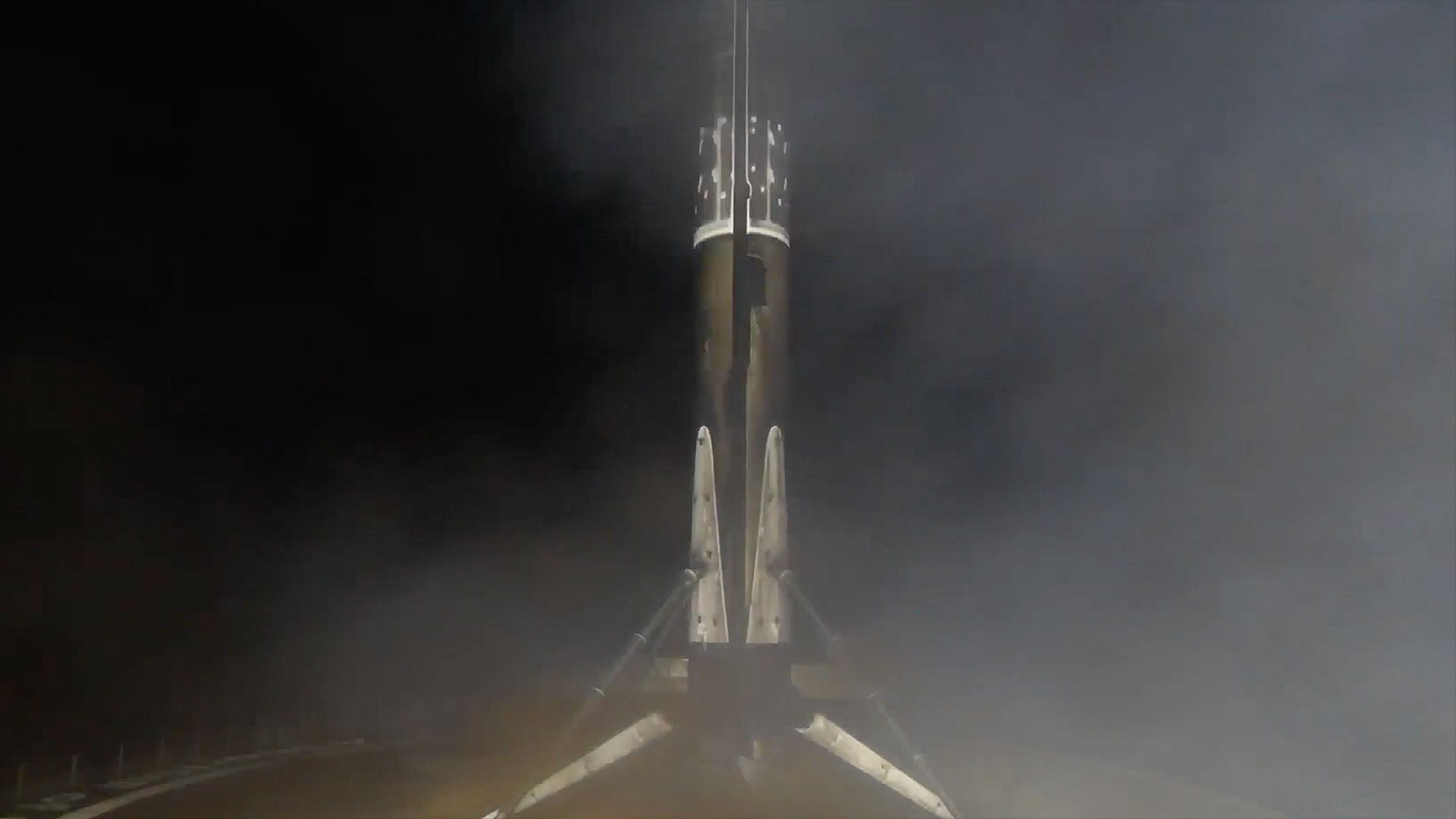 a first stage of a rocket stands on its four landing legs on an ocean-based droneship after a night launch