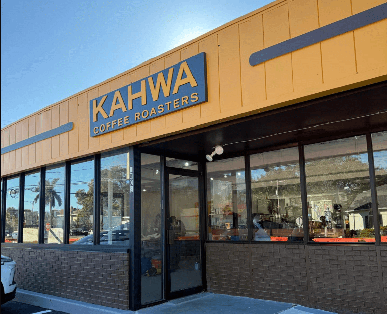 exterior of a Kahwa coffee shop with a mustard colored building top.