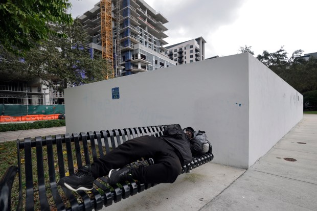 A man sleeps on a bench next to the sewer lift station Thursday at Peter Feldman Park in Fort Lauderdale. (Amy Beth Bennett/South Florida Sun Sentinel)