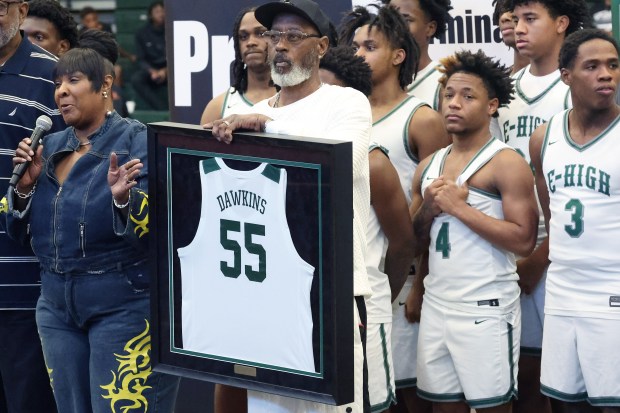 Amanda Dawkins (left) speaks as her fiance, Fredrick Johnson (middle) holds the framed jersey of former NBA star Darryl Dawkins during a jersey retirement ceremony at Evans High School on Saturday, January 24, 2026. NBA stars Darryl Dawkins (Chocolate Thunder) and Chucky Atkins both of whom were Evans High graduates, had their jerseys retired in the ceremony. Amanda is the sister of the legendary player. (Stephen M. Dowell/Orlando Sentinel)