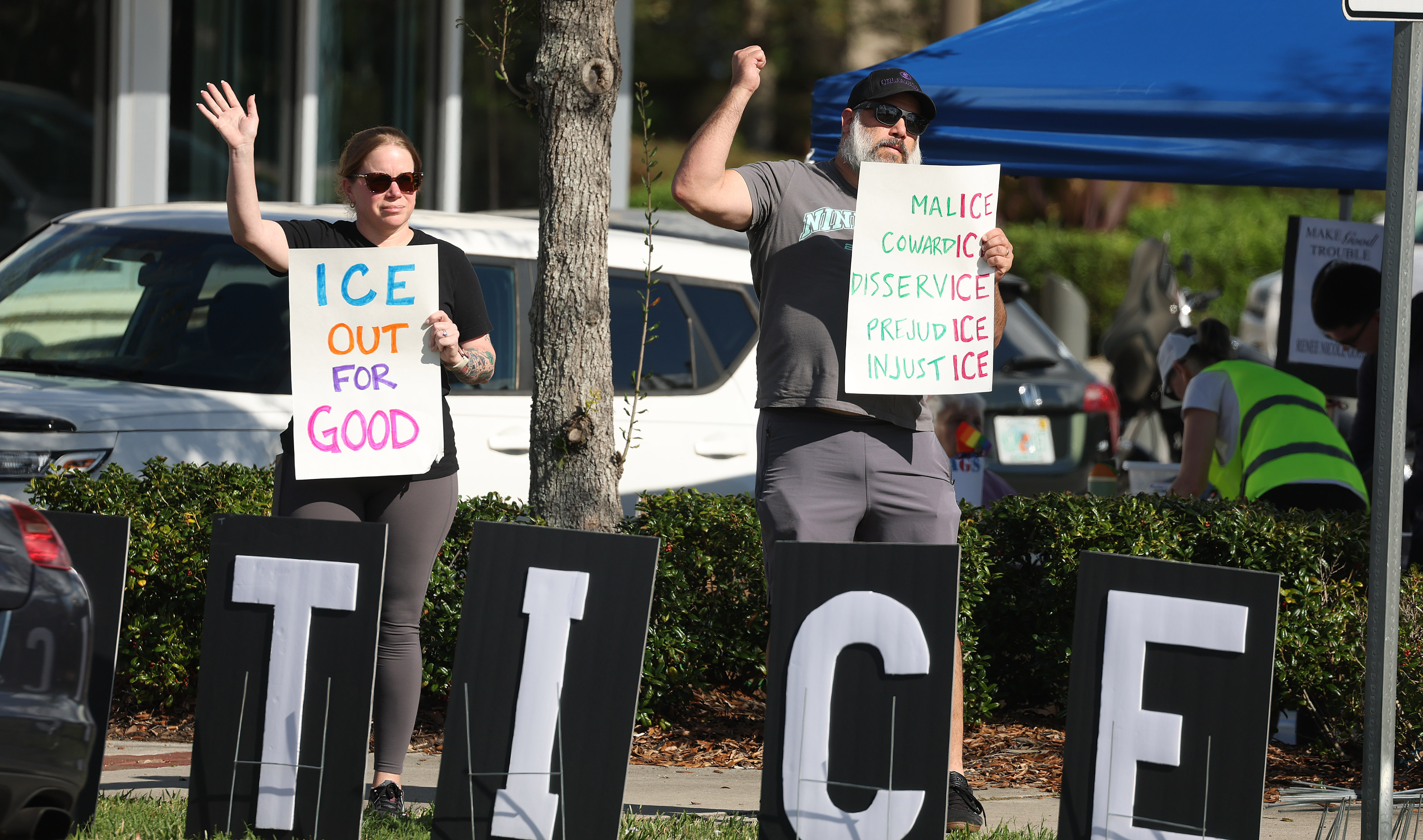Protestors chant and hold signs at passing traffic during a...