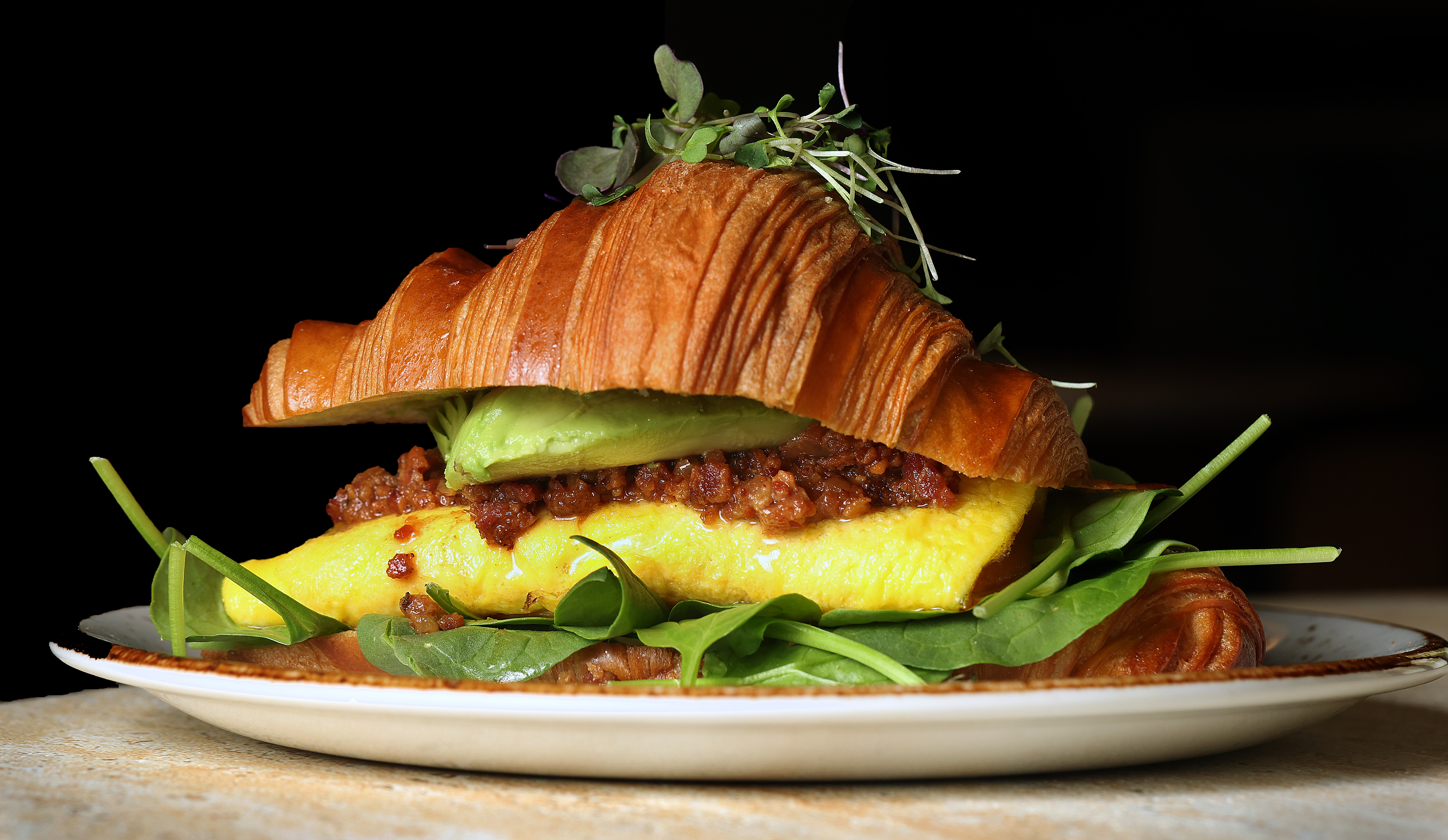 The Breakfast Croissant with cheddar eggs, bacon jam, avocado, tomato...