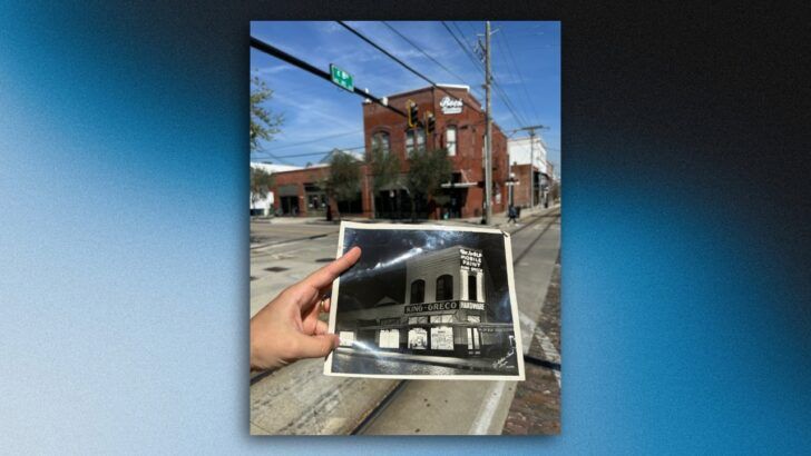 A hand holds a historic photograph of King-Greco Hardware in Ybor City, aligned with the same corner as it appears today.