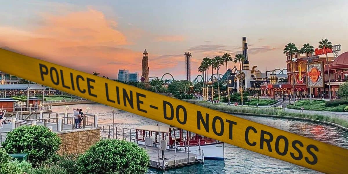Islands of Adventure at Universal Orlando Resort waterfront with boats and buildings at sunset is partially blocked by yellow "POLICE LINE – DO NOT CROSS" tape stretching across the foreground.