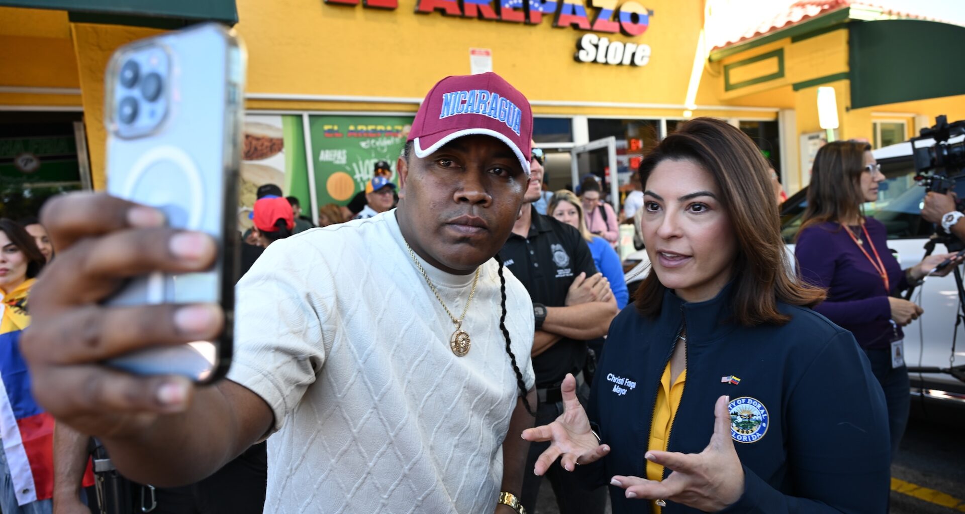 photo of a man posing for a selfie with Doral mayor Christi Fraga in front of a business named, "El Arepazo Store"