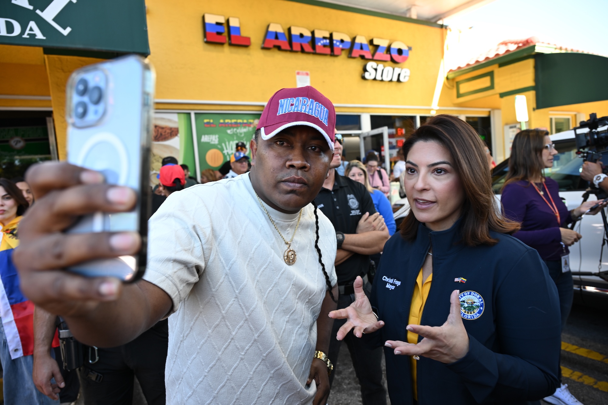 photo of a man posing for a selfie with Doral mayor Christi Fraga in front of a business named, "El Arepazo Store"