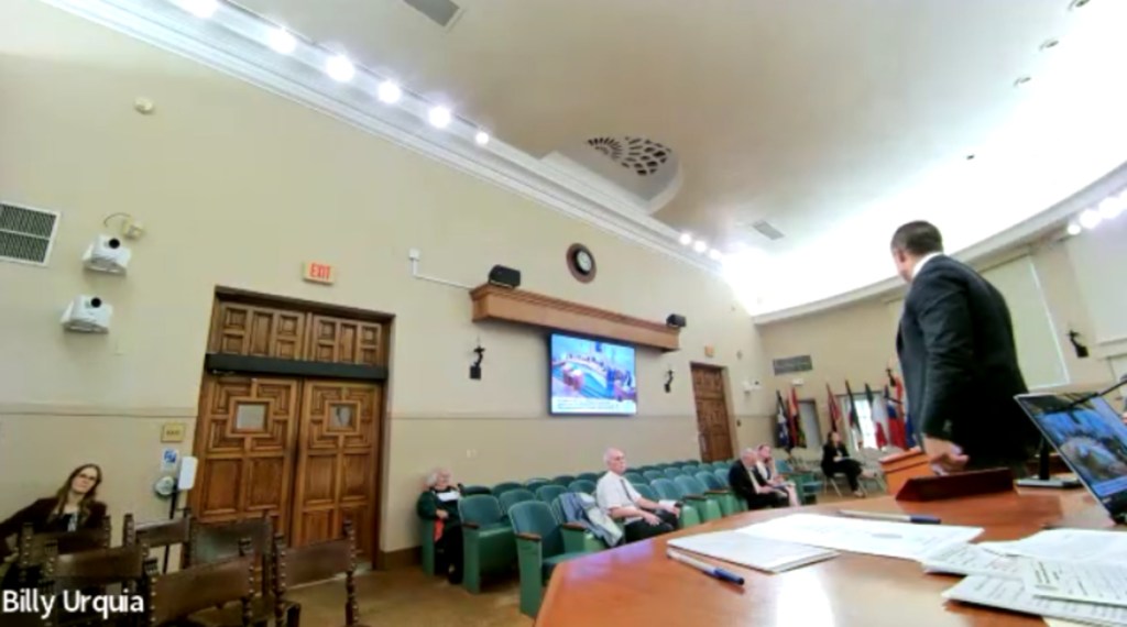 Vince Lago's back is to the camera as he speaks to the audience during the city commission meeting.