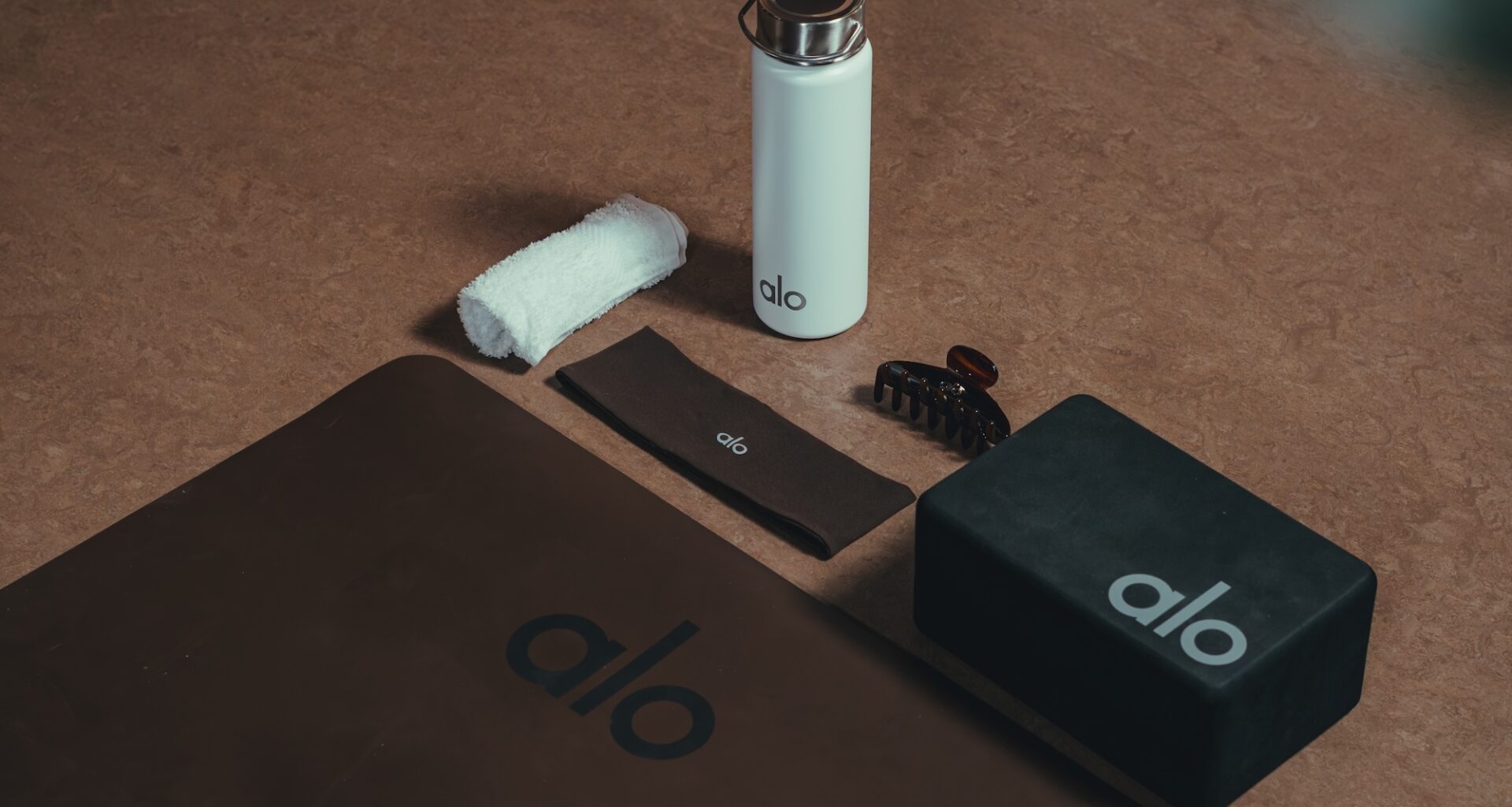 photo of a yoga mat, headband, yoga block, and water bottle with the brand name "Alo"