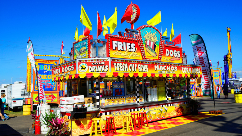 A colorful food concession stand selling fries, corn dogs, nachos, and drinks at Florida State Fair