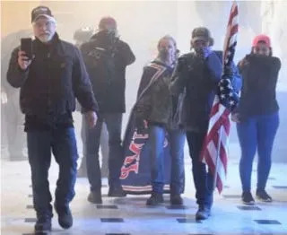 This image from inside the U.S. Capitol  was part of the initial court filing against Rachael Pert and Dana Joe Winn, who the FBI identified as the woman wearing a flag like a cape and the man with her carrying an American flag.