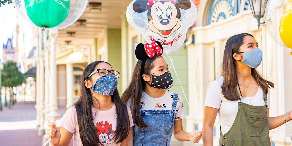Three young girls wear face masks at Magic Kingdom
