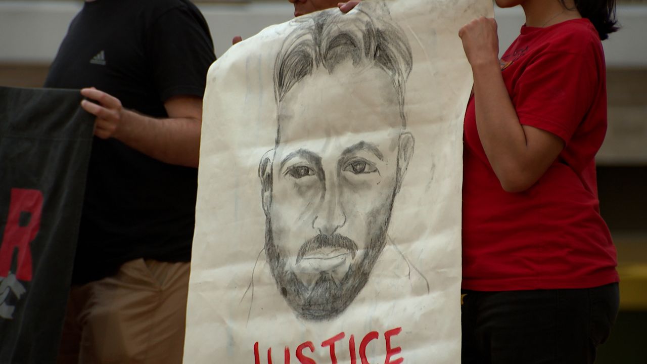 Demonstrators in Tampa hold a drawing of Alex Pretti, who was fatally shot by a federal immigration officer in Minneapolis. (Spectrum News)