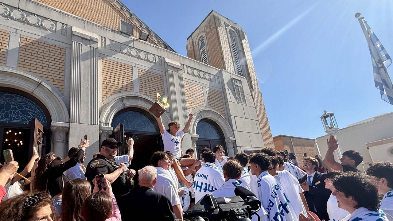 After retrieving the cross thrown into the Spring Bayou for 2026 Epiphany, 18-year-old Athos Karistinos celebrates with other cross divers at St. Nicholas Greek Orthodox Cathedral. (Spectrum News/Virginia Johnson)