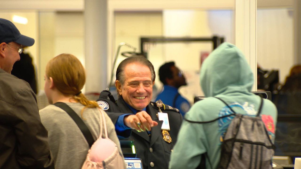A TSA workers reaches for a traveler's identification at Orlando International Airport. (Spectrum News/Phil Petersen)