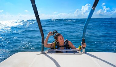 A woman smiles as she takes off her snorkeling mask while climbing aboard a boat.
