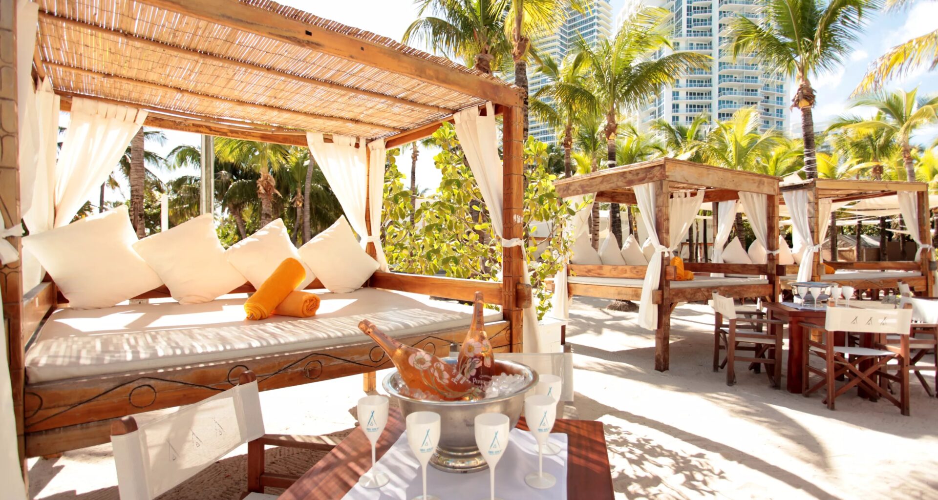 wooden cabanas and white furniture at Nikki Beach, a modern dayclub in Miami Beach
