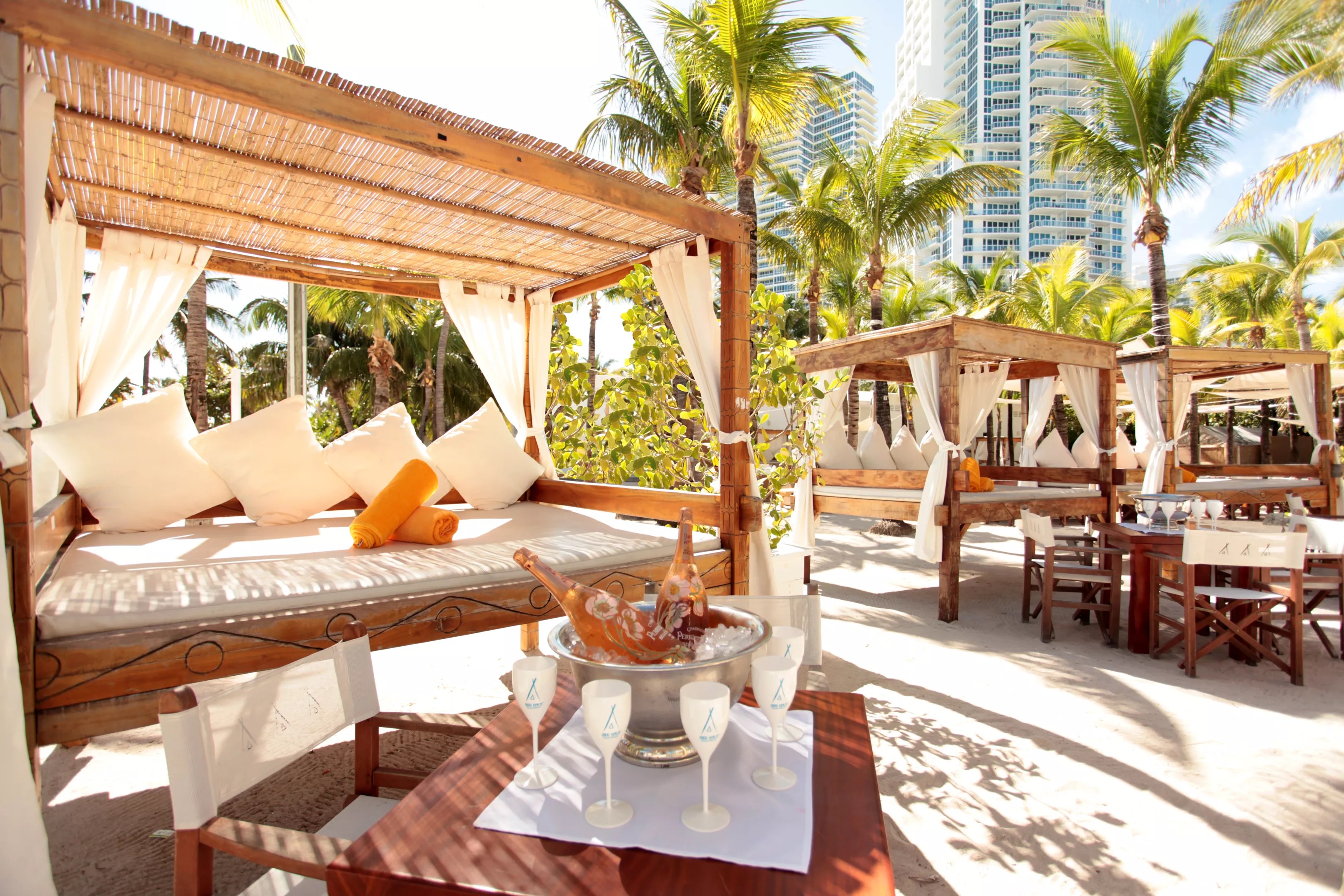 wooden cabanas and white furniture at Nikki Beach, a modern dayclub in Miami Beach