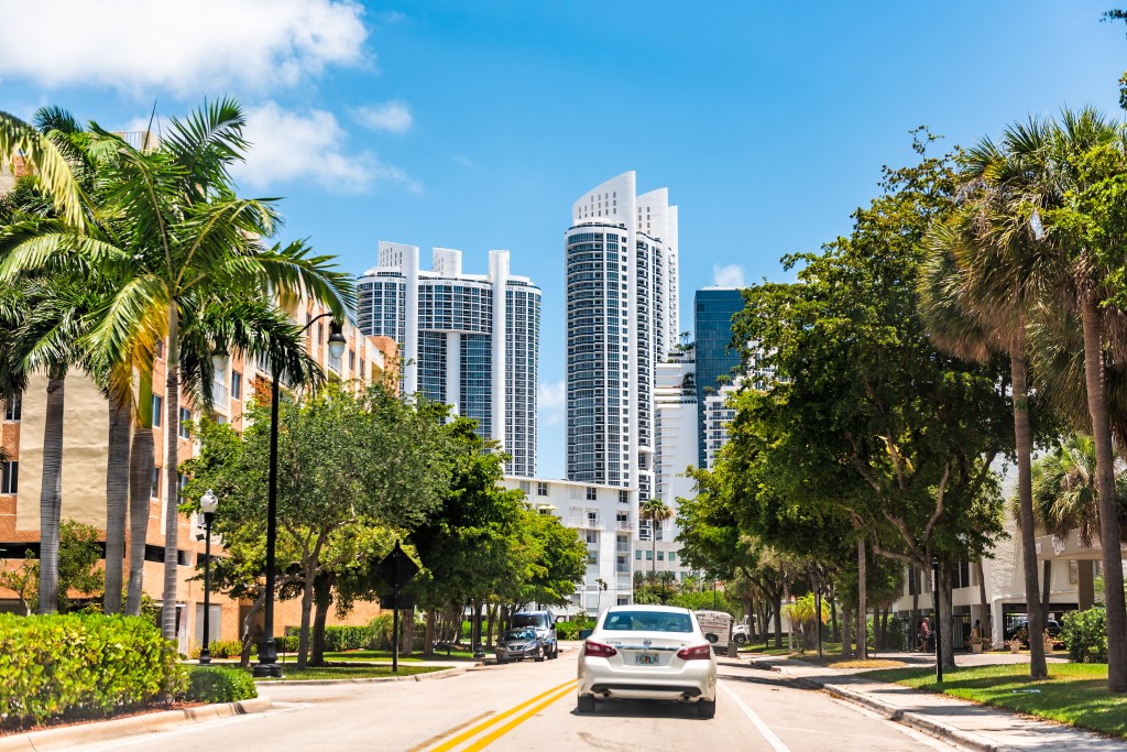 View of luxury hotel apartment buildings and palm trees on a street in Sunny Isles Beach, North Miami, Florida.
