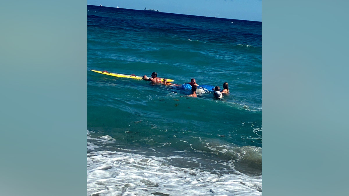 rescuers swimming to help paraglider in ocean