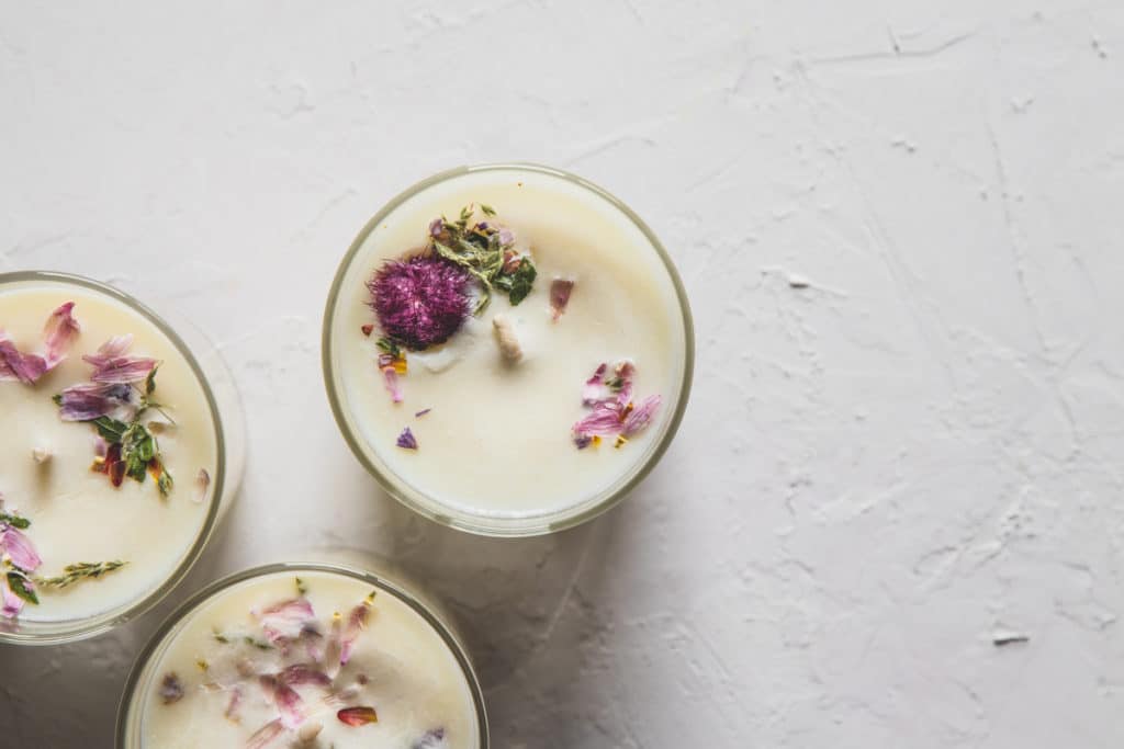Dried floral roses candles with rose quartz crystals on white background