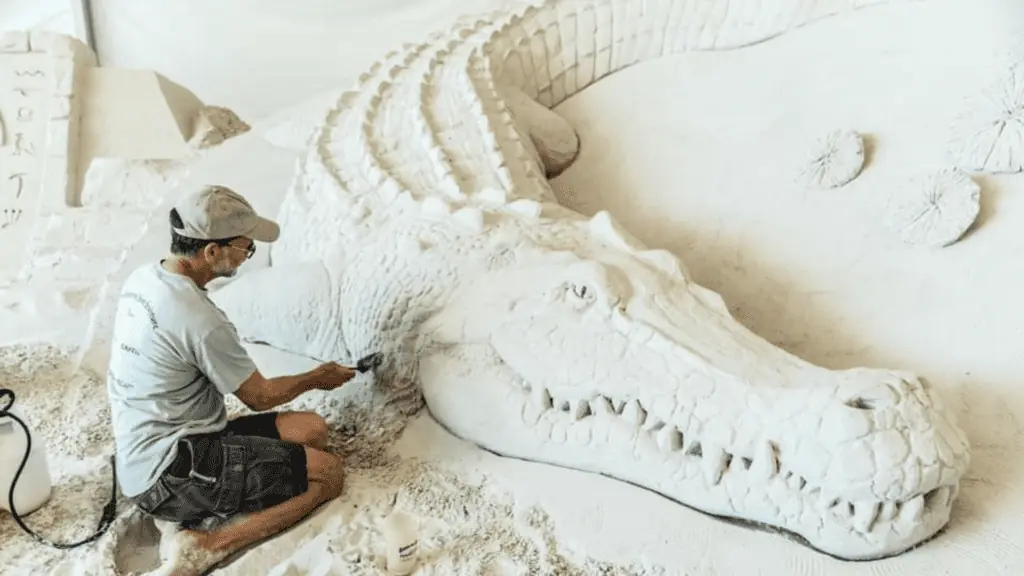 A sculptor creating a sand alligator
