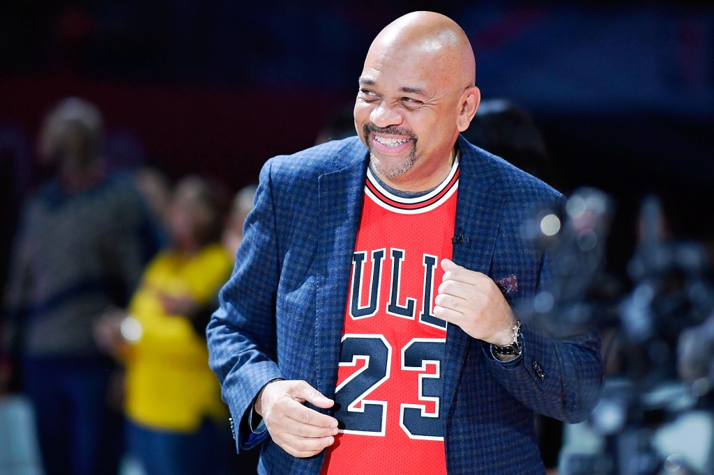 Michael Wilbon, coach of Team Wilbon, smiles while wearing a red Chicago Bulls jersey and a dark blue blazer.