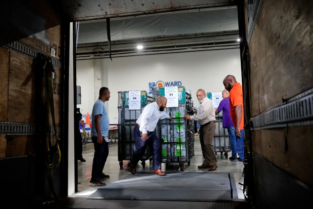 Broward County Supervisor of Elections Joe Scott, center, helps load the first cart of Vote-By-Mail ballots onto a USPS truck at the Supervisor of Elections Office in Fort Lauderdale Tuesday, Oct. 1, 2024. (Amy Beth Bennett / South Florida Sun Sentinel)