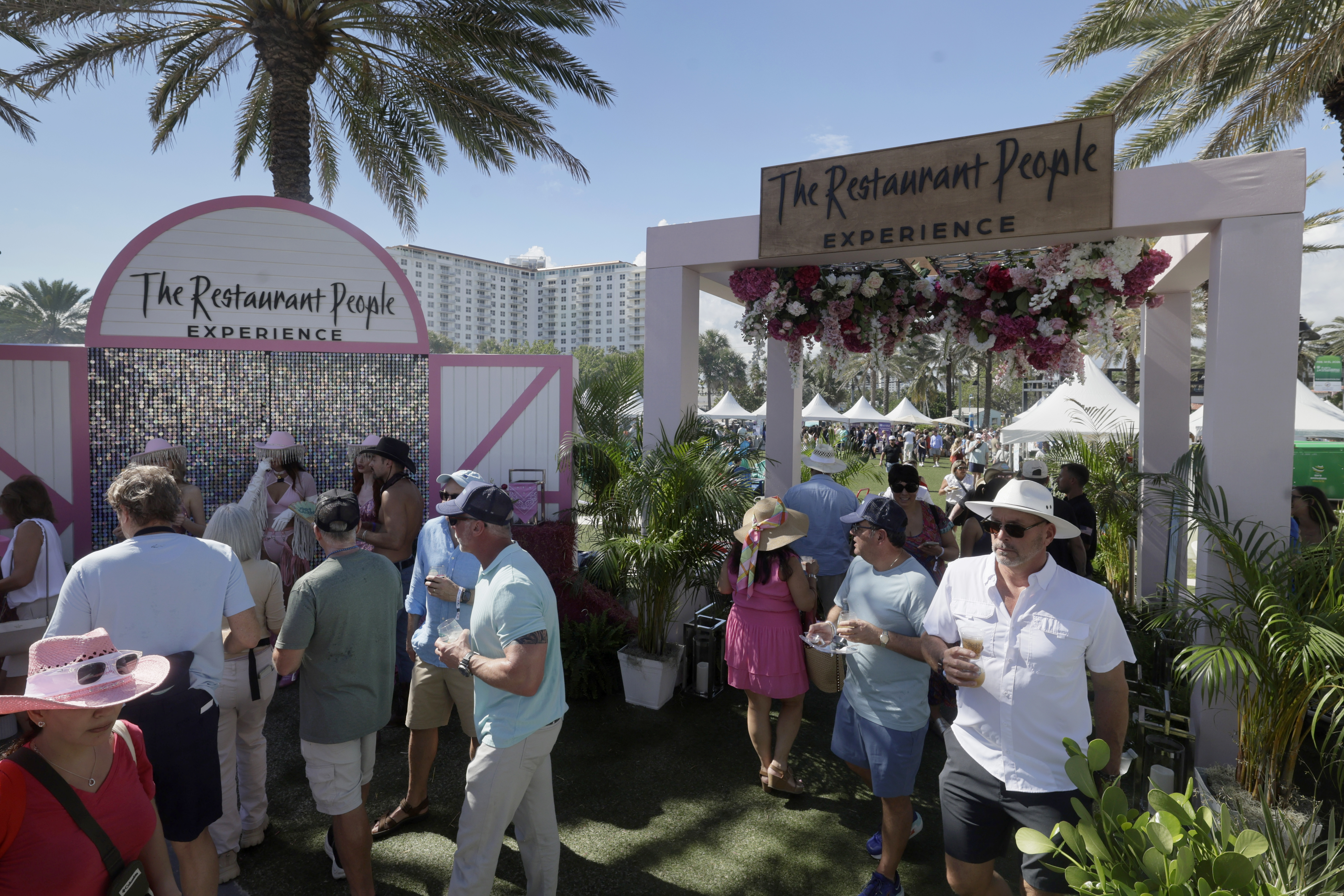 People gather under the palm trees during the Visit Lauderdale...