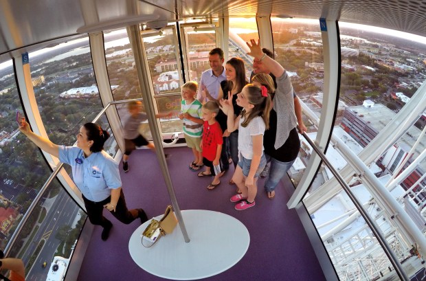 The capsule steward takes a selfie with riders during a sunset ride in one of capsules of the Orlando Eye at the I-Drive 360 complex on May 1, 2015. ( Joe Burbank/Orlando Sentinel file)