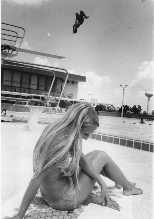 Ruth Graves, 20, an FTU junior from Jacksonville, reads the school's catalog at the pool as Richard Clark, 20, a sophomore dives off the board in this September 1972 photo. (Sentinel file)