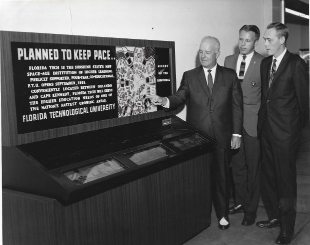 A FTU mobile exhibit is admired by President Charles Millican and officials of the Colonial Plaza Merchant Association. The exhibit was built for FTU by Graphics of Orlando and was touring Central Florida and other institutions in the fall of 1967 to "help tell the Florida Tech story" about the new "space-age university." (FTU Photo)