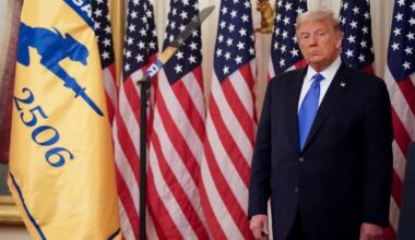 President Donald Trump stands in front of a lineup of American flags.