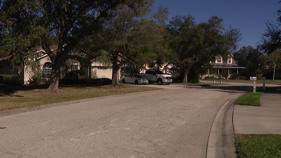 Residential street with two houses and vehicles parked in driveways.